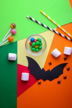Kağıt cadılar bayramı süslemeleri ve renkli kağıt üzerinde şekerler. Cadılar Bayramı konsepti. Düz yerde, üst tarafta. Dikey fotoğraf