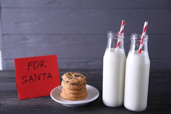 Leche y galletas sobre un fondo de madera gris con lugar para el texto. Leche y galletas para Santa Claus para Navidad — Foto de Stock