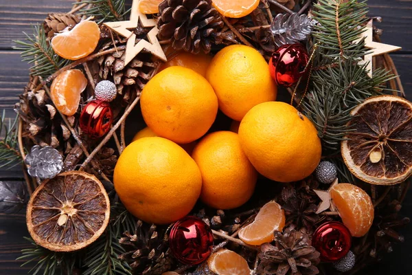 Christmas wreath is decorated with pine cones, toys and tangerines. — Stock Photo, Image
