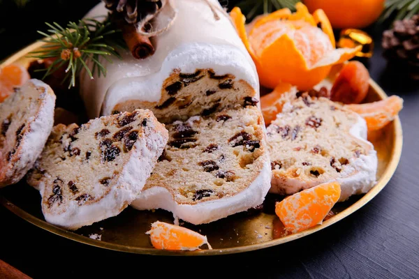 Classical Stollen is a Traditional German Cake with raisins and tangerines on dark background. Fruit cake for the Holiday. — Stock Photo, Image