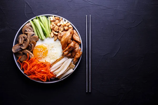 Bibimbap is a traditional dish of Korean cuisine on a dark background.