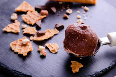 Koyu bir arka planda kaşıkta bir kepçe çikolatalı dondurma..