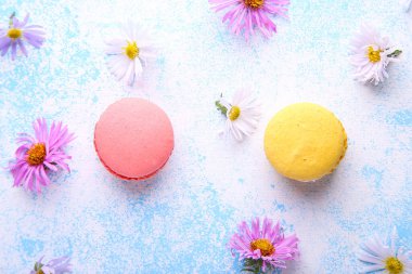 Mavi arka planda badem kurabiyesi ve çiçeklerle harika bir kompozisyon. Üst görünüm.