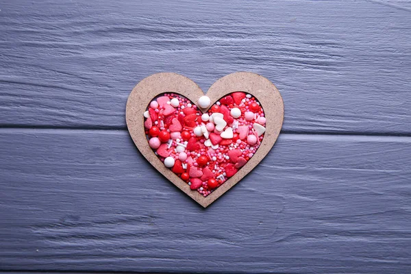 Heart of candy in wooden form on a grey background — Stock Photo, Image