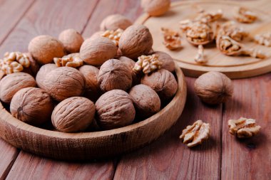 Kahverengi arka planda ahşap bir tabakta kabuklu cevizler. Sağlıklı gıda konsepti