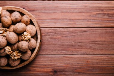 Kahverengi arka planda ahşap bir tabakta kabuklu cevizler. Sağlıklı gıda konsepti