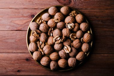 Kahverengi arka planda altın bir tabakta kabuklu cevizler. Sağlıklı gıda konsepti
