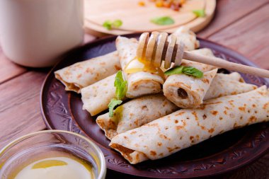 Süzme peynirli krep, kuru üzüm ve bal ahşap arka planda..