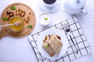 Süzme peynirli krep, kuru üzüm ve bal ahşap arka planda..