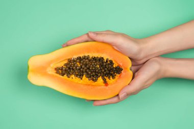 Yeşil arka planda kadın ellerinde Papaya meyvesi. Tropik meyve. Yarım papaya.. 