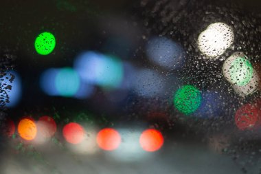 Yağmur damlaları ve ışıklarla bulanık arkaplan.