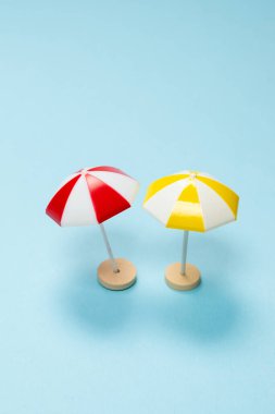 Mavi arka planda sarı ve kırmızı şemsiye. Boşluğu kopyala.