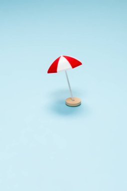 Seyahat konsepti. Güneş şezlongu, mavi arka planda kırmızı şemsiye. Boşluğu kopyala. 