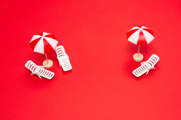 两个日光浴者和红色背景的红色雨伞 复制空间 — 图库照片