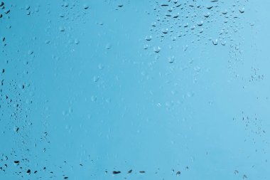 Su damlaları olan mavi bir sırt sırtı. Islak cam. Boşluğu kopyala. 