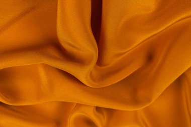 Altın ipek ya da saten lüks kumaş dokusu soyut bir arkaplan olarak kullanılabilir. Üst görünüm.