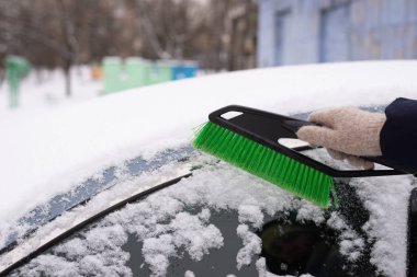 Kar temizleme, karlı araba. Kadın arabayı kardan temizliyor..