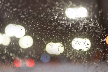 Yağmur damlaları ve ışıklarla bulanık arkaplan.