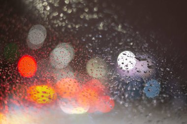 Yağmur damlaları ve ışıklarla bulanık arkaplan.