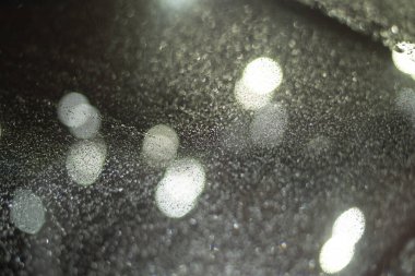 Yağmur damlaları ve ışıklarla bulanık arkaplan.