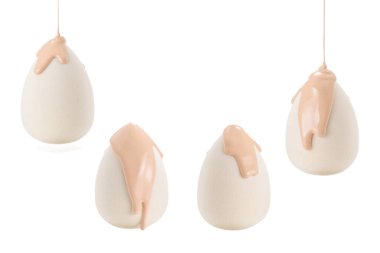 Beyaz arka planda izole edilmiş yeni beyaz süngerin üzerine dökülen sıvı bej makyaj vakfı