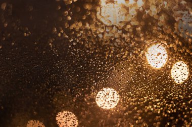 Yağmur damlaları ve ışıklarla bulanık arkaplan.