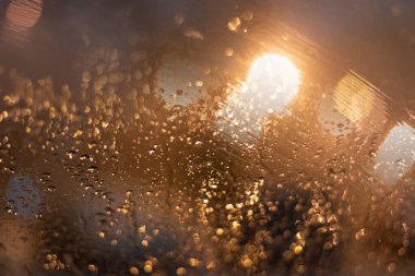 Yağmur damlaları ve ışıklarla bulanık arkaplan.