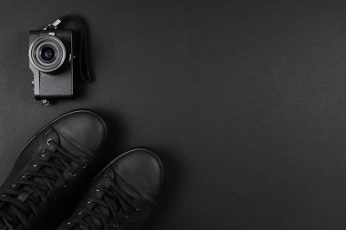 Siyah deri ayakkabılar ve siyah arka planda siyah bir kamera. Boşluğu kopyala.