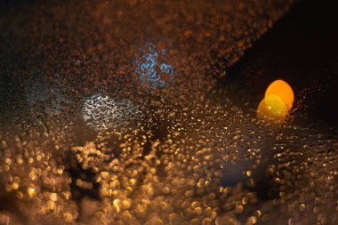 Yağmur damlaları ve ışıklarla bulanık arkaplan.