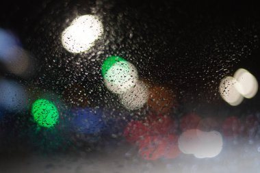 Yağmur damlaları ve ışıklarla bulanık arkaplan.