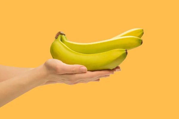 Een Stelletje Bananen Hand Van Een Vrouw Geïsoleerd Een Oranje — Stockfoto