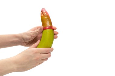 Kadın, muza prezervatif takmış. Beyaz bir arkaplanda izole edilmiş. 