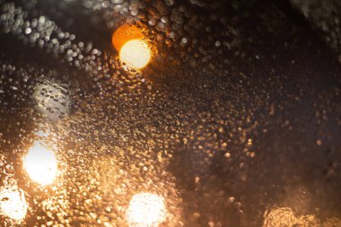 Yağmur damlaları ve ışıklarla bulanık arkaplan.