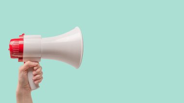 Yeşil arka planda kadın eli olan megafon. Boşluğu kopyala. 