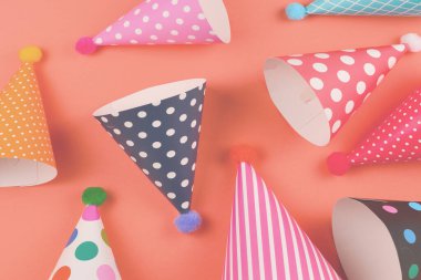 Turuncu arka planda renkli doğum günü şapkaları. Üst görünüm.