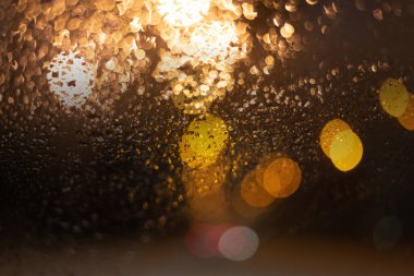 Yağmur damlaları ve ışıklarla bulanık arkaplan.