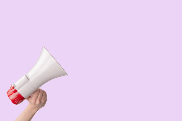Мегафон в женских руках на розовом фоне. Копирование пространства. 