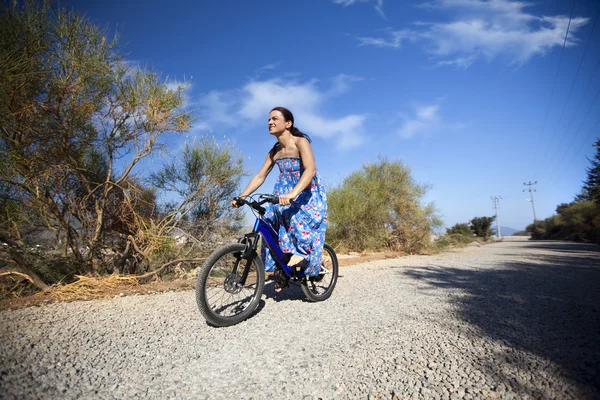 Krásná usměvavá dívka jezdí na kole na silnici vesnice — Stock fotografie