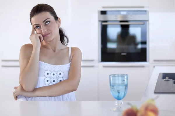 Portrait of a beautiful woman thinking at the kitchen counter — Stock Photo, Image