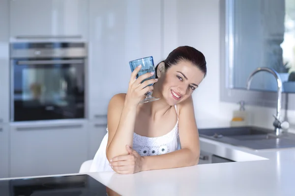 Ritratto di una bella donna che tiene un bicchiere in cucina — Foto Stock