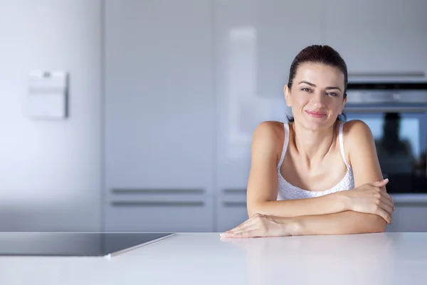 Portrait of a cheerful woman at the kitchen counter — Stock Photo, Image