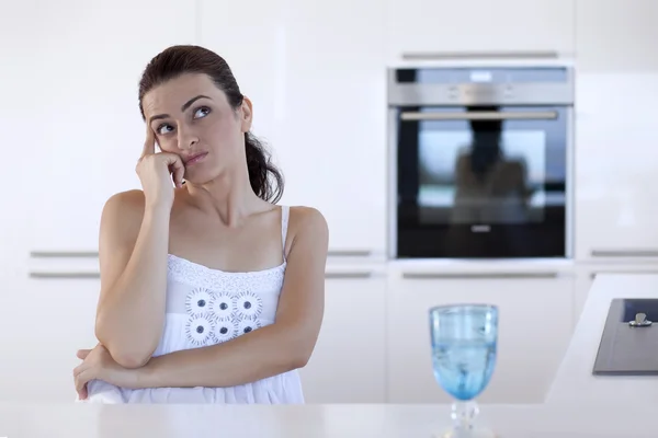 Portrait of a smiling woman thinking at the kitchen counter — Stock Photo, Image