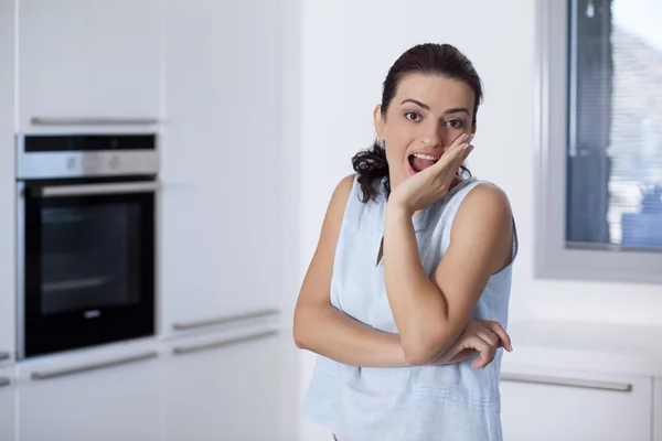 Portrait of a surprised woman at the kitchen counter — Stock Photo, Image