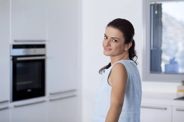 Beautiful smiling woman look to us in the kitchen — Stock Photo, Image