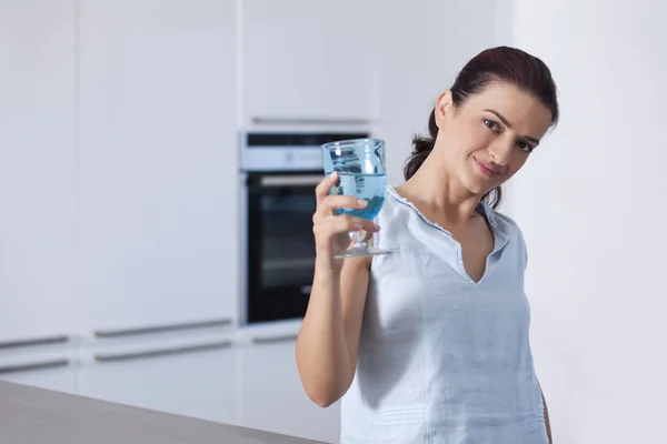Retrato de uma bela mulher segurando um copo na cozinha — Fotografia de Stock