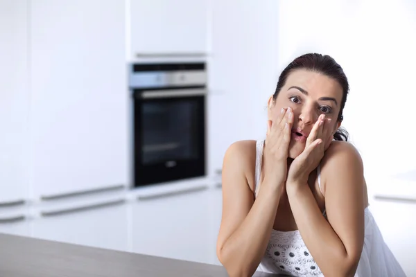 Portrait of a surprised woman at the kitchen counter — Stock Photo, Image