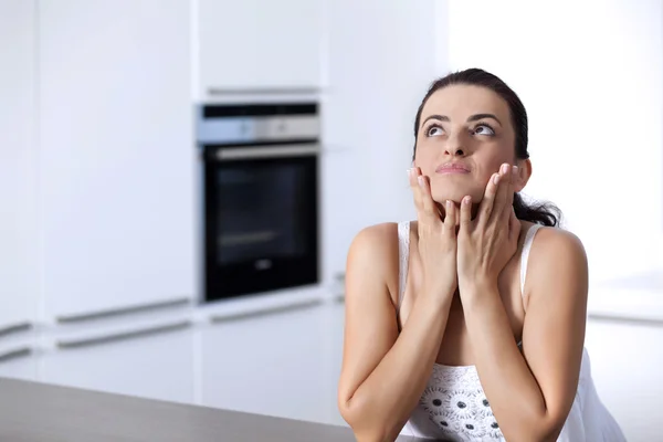 Portrait of a beautiful woman thinking at the kitchen counter — Stock Photo, Image