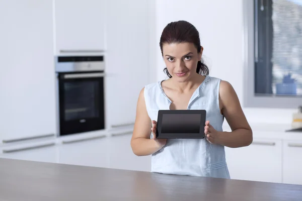 Νεαρή γυναίκα που δείχνει μια ψηφιακή δισκίο σε το της κουζίνας — Φωτογραφία Αρχείου