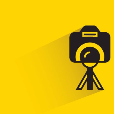 digital camera on tripod with shadow on yellow background