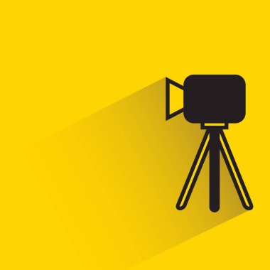 camera on tripod with shadow on yellow background